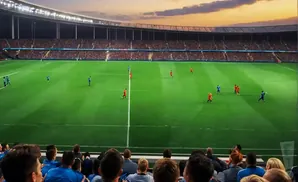 Soccer game at sunset in a stadium with a crowd of spectators.