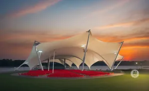 Outdoor amphitheater with red seats under a large white tent at sunset.