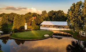 A golf course and a large white tent at sunset.