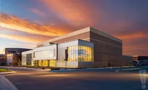 Modern building with large glass windows against a vibrant sunset sky.