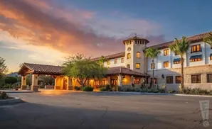 A Spanish-style hotel with a tower and arched entrance at sunset.