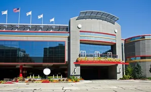 Modern building with large glass windows, flags, and colorful flowerbeds.