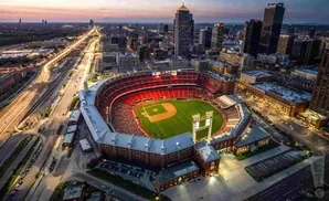 Aerial view of Busch Stadium during a baseball game at dusk, with city skyline in background.