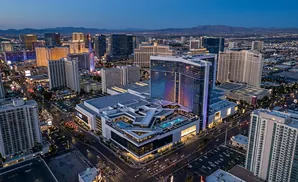 Aerial view of Las Vegas Strip hotels and casinos at dusk, with illuminated buildings and city lights.