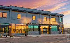 Modern building with large windows reflecting a colorful sunset sky.