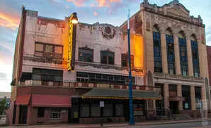 Exterior of a historic theater with an illuminated marquee and ornate architectural details at dusk.