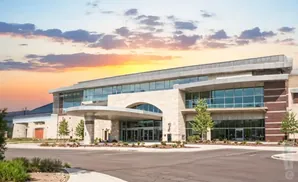 Modern building with arched entrance and large glass windows during a colorful sunset.