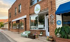 A brick storefront with a blue awning and signs featuring a green leaf logo.
