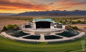 Outdoor amphitheater with rows of dark green seats, a stage, and mountains under a vibrant sunset.