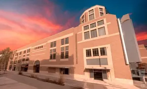 Brick building with large windows under a vibrant sunset sky.