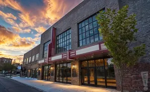 A brick building with large windows and a marquee at sunset.