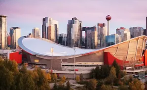 Skyline of Calgary, Canada, featuring the Saddledome arena and modern skyscrapers at sunset.