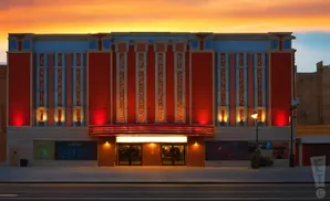 An Egyptian-themed theater building at sunset, with glowing red lights and hieroglyph-like carvings.