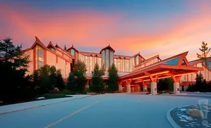 A hotel with an orange roof is lit up under a pink and orange sunset sky.