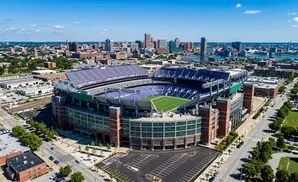 Aerial view of a large, empty football stadium in a city with a skyline in the distance.