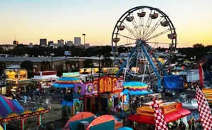 An amusement park with a Ferris wheel and colorful rides under a sunset sky.