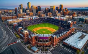 Aerial view of Coors Field baseball stadium in Denver, Colorado, with downtown skyscrapers in the background.
