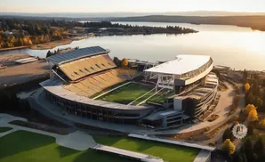Aerial view of a football stadium on a sunny day, with a large body of water in the background.