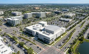 Aerial view of a modern business district with office buildings, parking lots, and a lake.