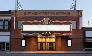 Marquee of a classic movie theater with neon lights, a blank display, and three stars above double red doors.