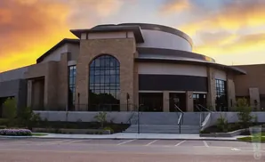 Modern building with stone accents and arched windows under a vibrant sunset sky.