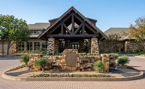A stone building with a wooden covered entrance and a circular paved driveway in front.