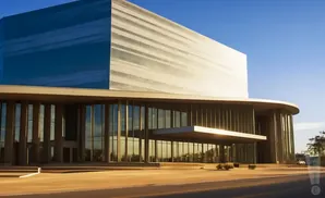 Modern building with a blue glass upper section and glass-paneled lower section, under a clear blue sky.