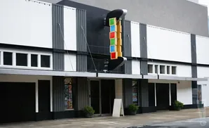 Exterior of a modern cinema with a vertical marquee displaying colored squares.