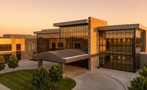 Modern office building with stone accents and large glass windows at sunset.
