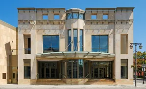 Modern stone building with large glass windows and doors under a metal awning.