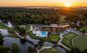 Aerial view of a golf course club house and pool at sunset.