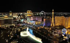 Las Vegas Strip at night, featuring the Eiffel Tower replica, the High Roller observation wheel, and the Bellagio fountains.