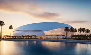 Modern stadium with a curved, glass facade and white roof, surrounded by palm trees and reflected in a body of water at sunset.