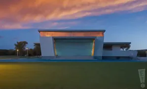 Modern white building with a glass stage front, against a sunset sky.
