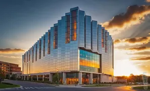 Modern glass building with tiered facade reflects a vibrant sunset.