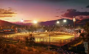 A rodeo arena at sunset with a crowd in the stands.