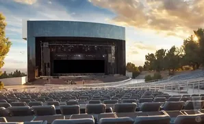 Outdoor amphitheater stage at sunset with rows of empty seats in the foreground.