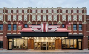 Art Deco theater marquee with red and white neon lights above a brick building facade with decorative tile work.