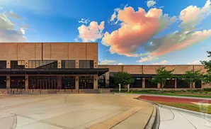 A modern brick building with large windows and a cloudy sky.