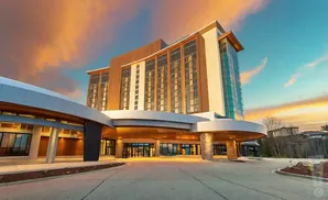 Modern hotel entrance with curving canopy and sunset sky.