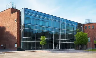 A modern glass and brick building with trees in front.