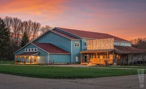 A light blue barn with a red roof at sunset.