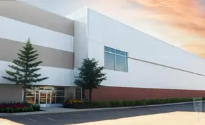 Modern industrial building with large white panels, a red base, and a large window.