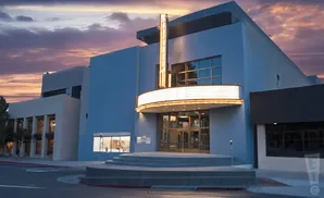 A blue theater with a lit marquee at dusk.