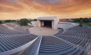 An outdoor amphitheater at sunset with rows of seats facing a stage.