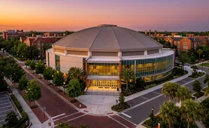 Aerial view of a circular, domed arena on a university campus at sunset.