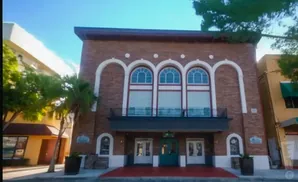 A brick building with arched windows and a red carpet leading to its entrance.
