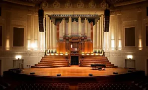 Grand organ and stage with a grand piano in a concert hall.