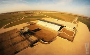 Aerial view of a rodeo arena with grandstands, holding pens, and a concession building.