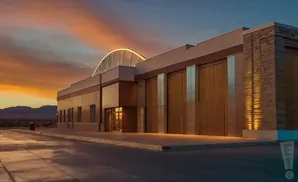 Modern building with a curved glass roof at sunset.